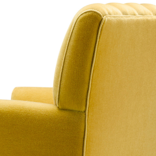 Close-up of a mustard yellow upholstered armchair with a curved backrest.