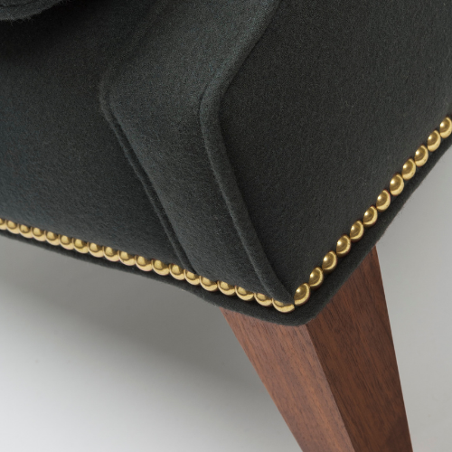 Close-up of a black upholstered chair with gold nailhead trim and wooden legs.