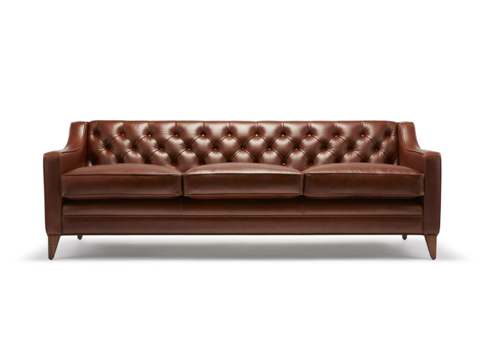 Brown leather tufted sofa with three seat cushions, wooden legs, and a classic design, set against a white background.