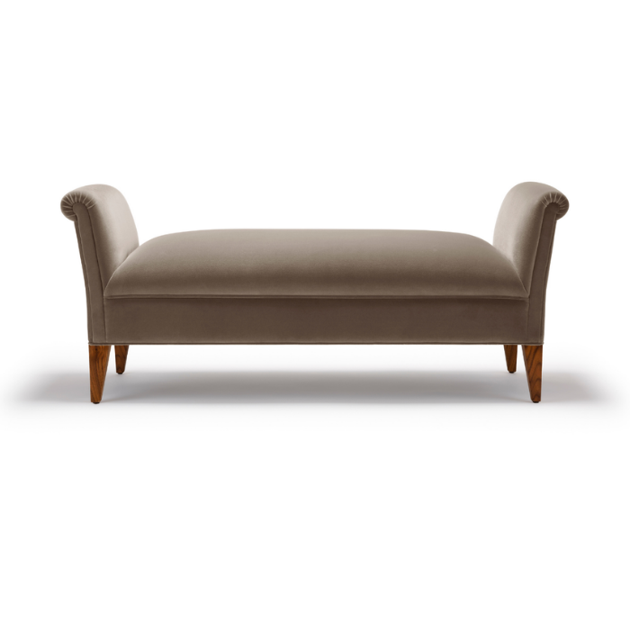 A beige upholstered bench or ottoman with rolled arms and wooden legs.