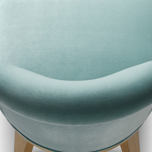 Close-up of a light blue upholstered chair with wooden legs, showing the curved seat and backrest.