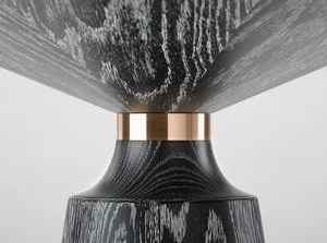 Close-up of a black wooden table or stand with a polished rose gold metal band connecting the top and the base.