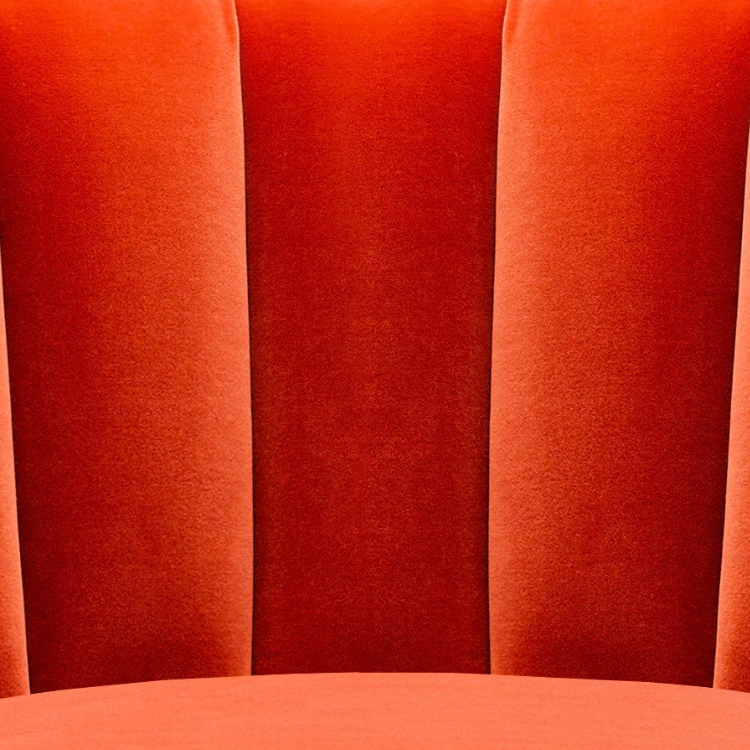 Close-up of red upholstered theater or auditorium seats with vertical paneling.