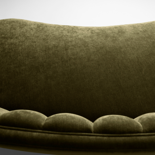 Close-up of a green velvet sofa with a rounded backrest and a tufted seat.