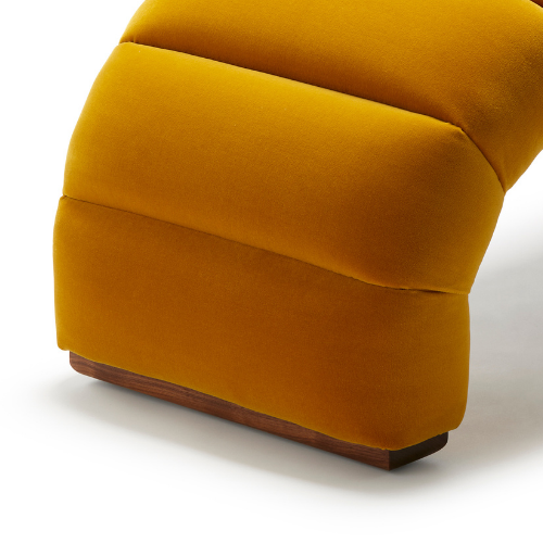 Close-up of a mustard yellow upholstered armchair with a wooden base.