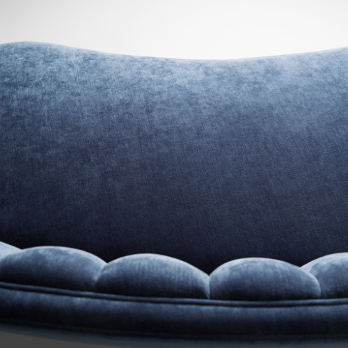 Close-up of a blue velvet sofa with rounded cushions.