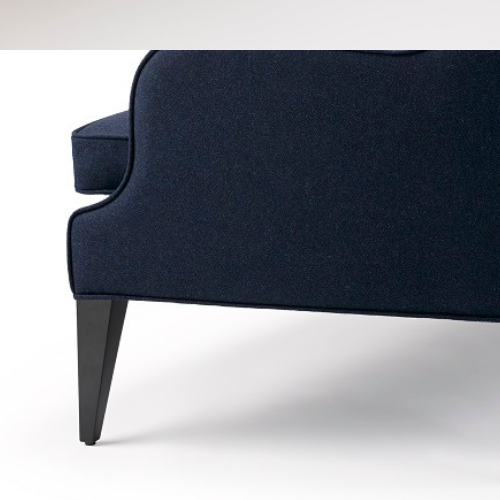Close-up of the bottom corner of a dark blue upholstered sofa with black tapered legs.