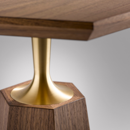Close-up of a piece of wooden furniture with a gold-colored decorative element connecting the top and base.