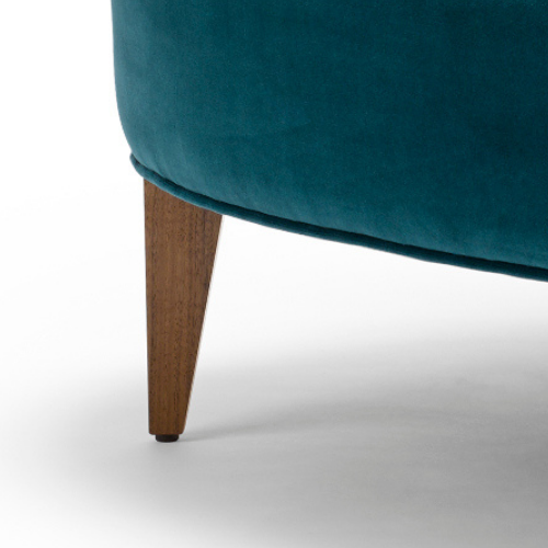 Close-up of a teal upholstered chair with a wooden leg.