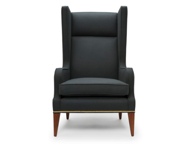 A high-backed, black upholstered armchair with wooden legs and nailhead trim at the bottom.