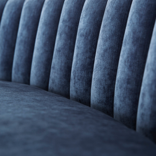 Close-up of a blue velvet sofa with vertical tufted upholstery.