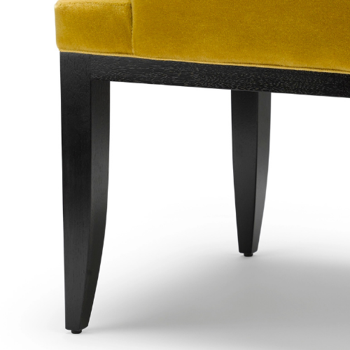 Close-up of a yellow upholstered chair with black wooden legs.