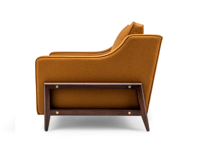Side view of a mid-century modern orange-brown armchair with a wooden side table attached underneath.