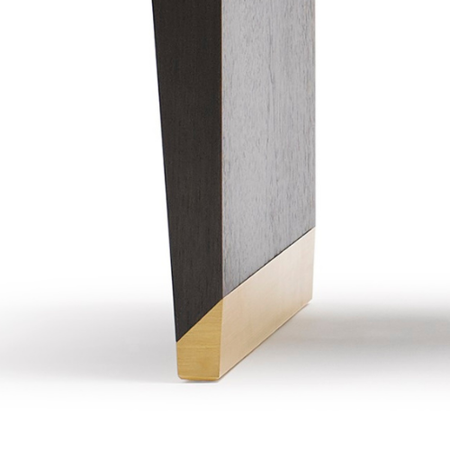 Close-up of the bottom corner of a modern piece of furniture, showing a black or dark gray panel and a gold-colored metal or decorative base.