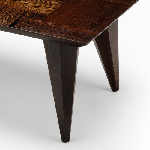 Close-up of a wooden table with dark, polished finish showing two tapered legs.