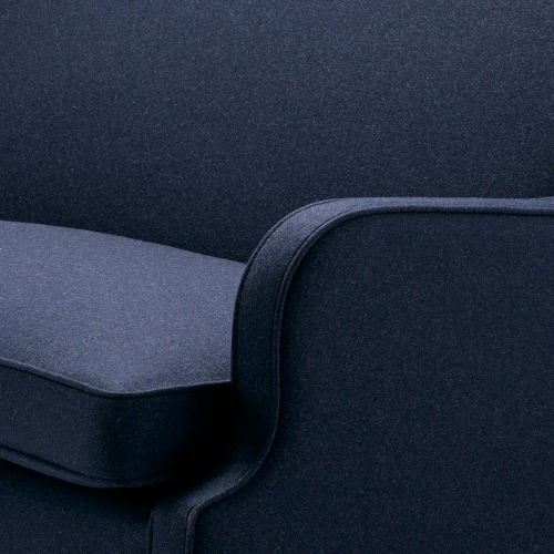 Close-up of dark blue upholstered sofa with curved armrest