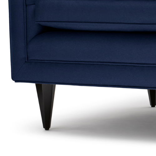 Close-up of a dark blue upholstered sofa with black tapered legs.