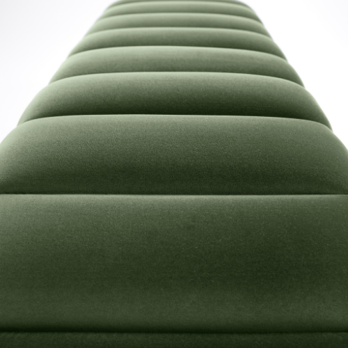 Green padded bench or seating area with a curved design, photographed from a low angle