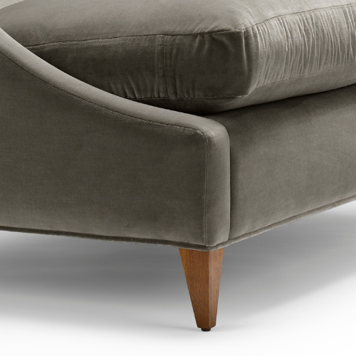 Close-up of a modern gray fabric sofa with a wooden leg.