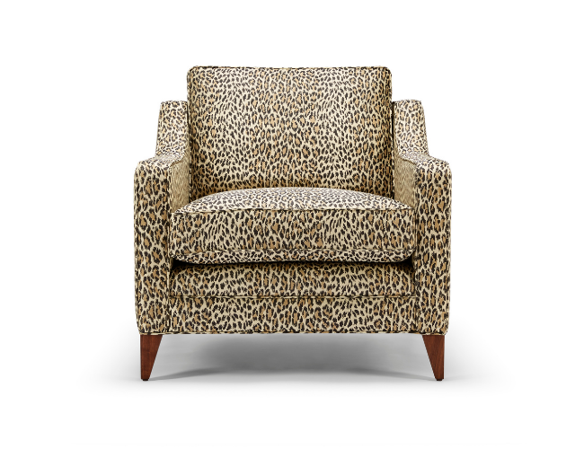 Leopard print armchair with wooden legs.