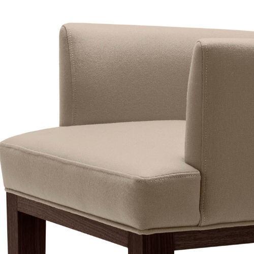 Close-up of a beige upholstered armchair with wooden legs.
