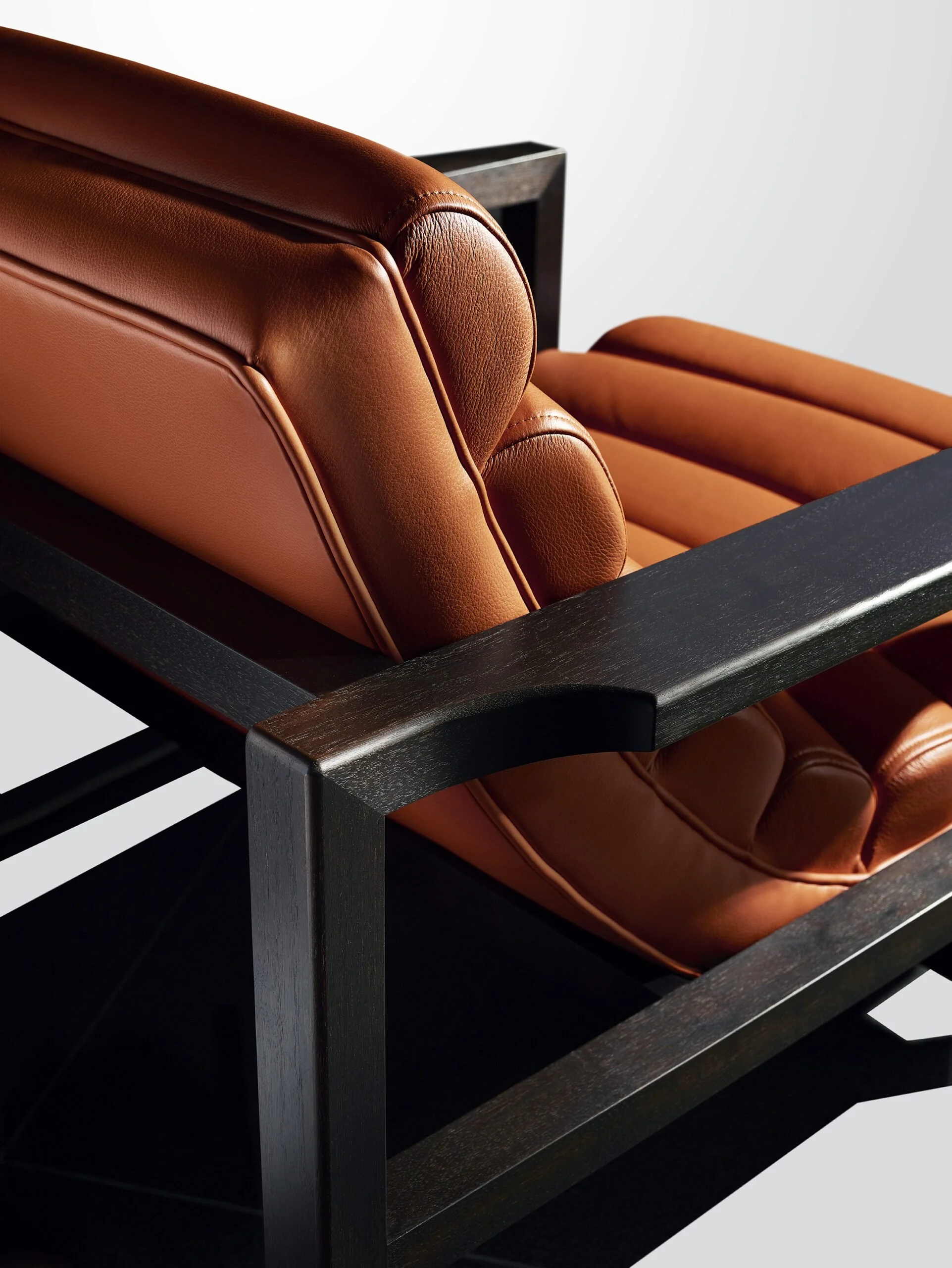 Close-up of a Florence Easy Chair, a brown leather armchair with a black wooden frame made for the McLaren showroom.