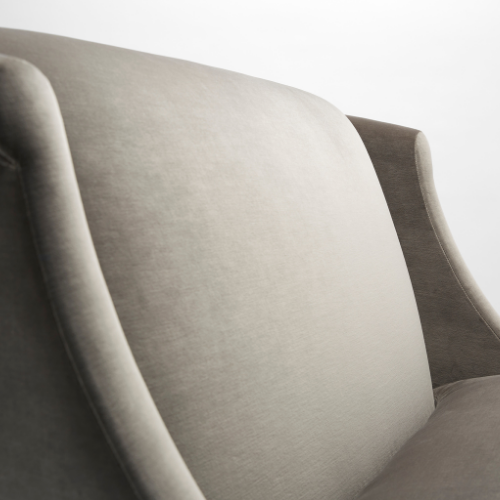 Close-up of an upholstered beige chair with a curved backrest.