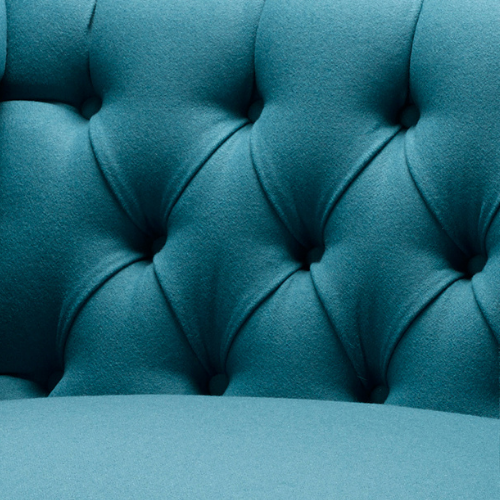 Close-up of teal upholstered tufted furniture with button detailing.