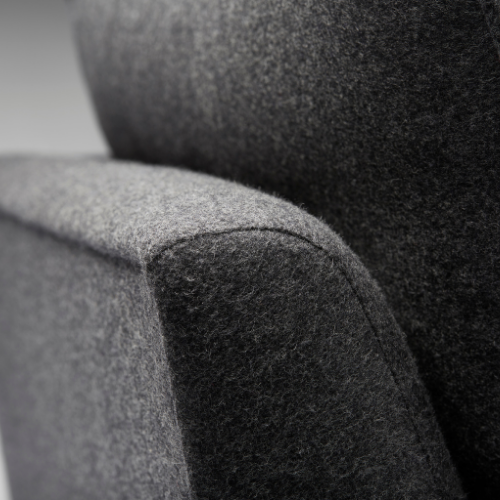 Close-up of a dark grey upholstered armchair's corner with textured fabric.