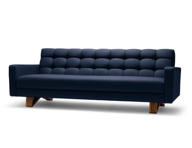 Navy blue upholstered sofa with tufted back and wooden legs on a white background.