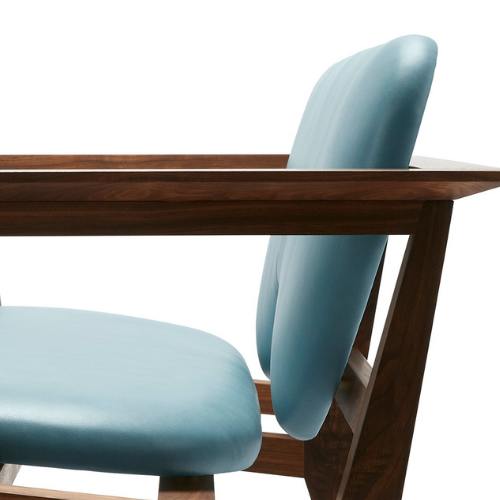 Close-up of a wooden dining table with a padded, light blue upholstered chair.