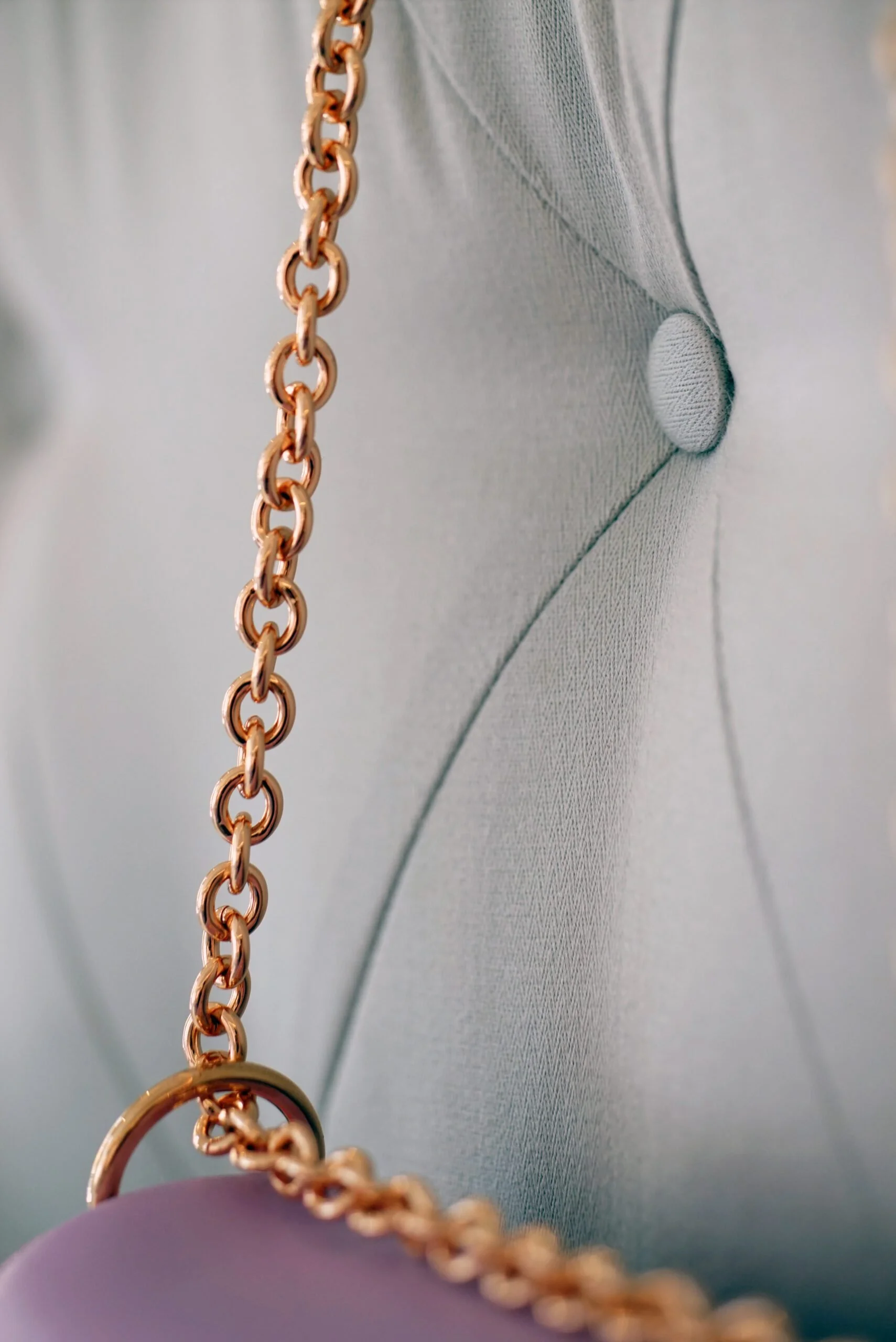 Close-up of a rose gold chain hanging against a textured, padded fabric surface.