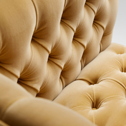 Close-up of a beige tufted upholstered furniture piece, showing detailed button and seam work.