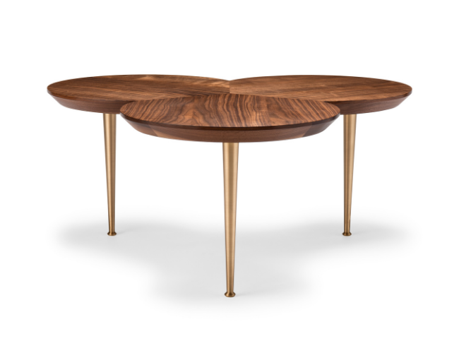 A modern wooden dining table with a rounded, overlapping top design and four tall, slender metal legs.