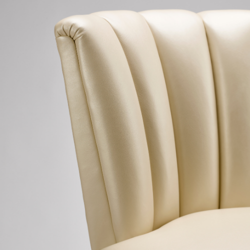 Close-up of a beige upholstered chair with a padded, rounded backrest.