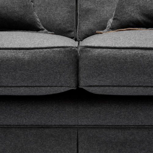Close-up of a dark gray fabric sofa with two cushions and a small tear on the right cushion.