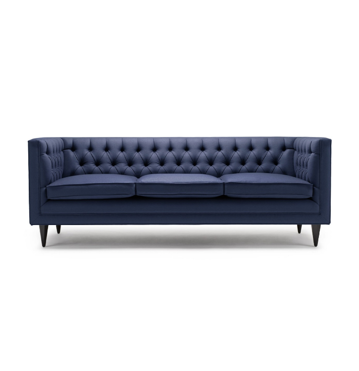 A dark blue upholstered three-seater sofa with tufted back and armrests, four black tapered legs, isolated on white background.