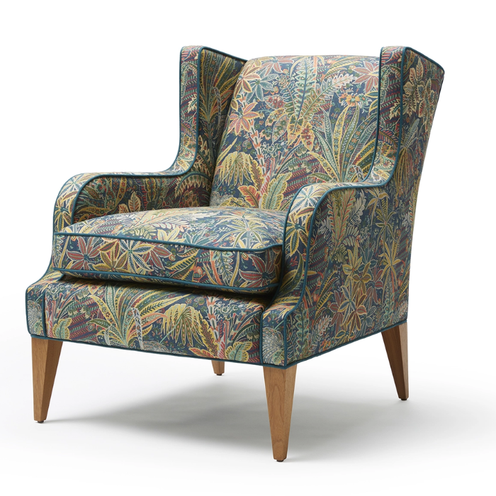 A upholstered armchair with a colorful floral pattern, wooden legs, and a high back.