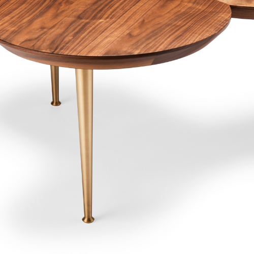 Close-up of a wooden table with a rounded edge and gold-colored tapered metal legs.