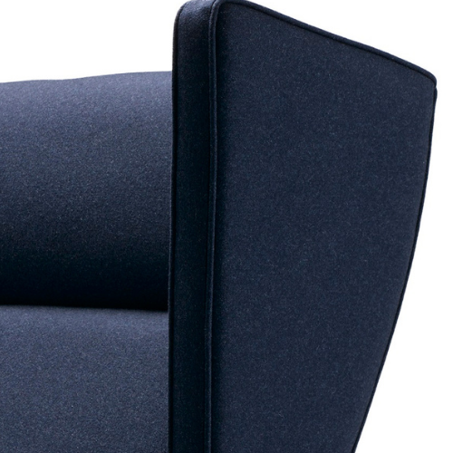 Close-up of a dark blue upholstered armchair with a high backrest.