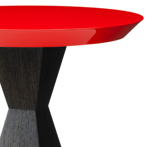 Close-up of a modern side table with a red round top and a black wood-textured support.