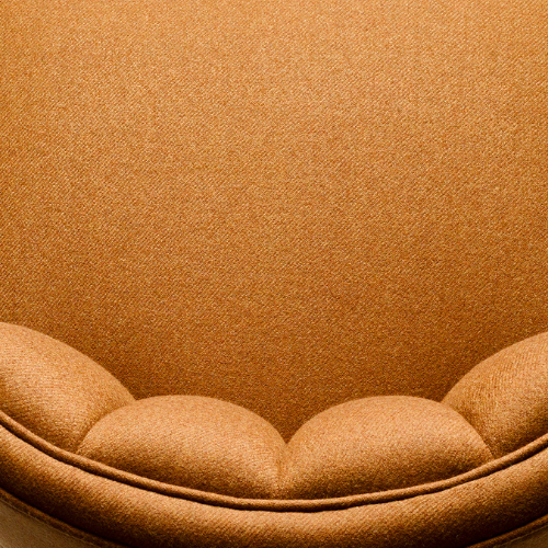 Close-up of a round, plush, beige cushion with a textured fabric background.