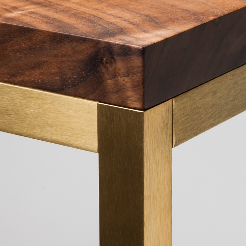 Close-up of a piece of wooden furniture with a dark stained top and a gold-colored leg.
