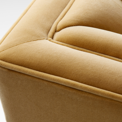 Close-up of a beige upholstered armrest or cushion showing fabric texture and stitching.