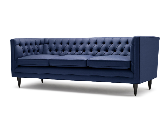 Blue tufted sofa with three seat cushions and tapering legs.