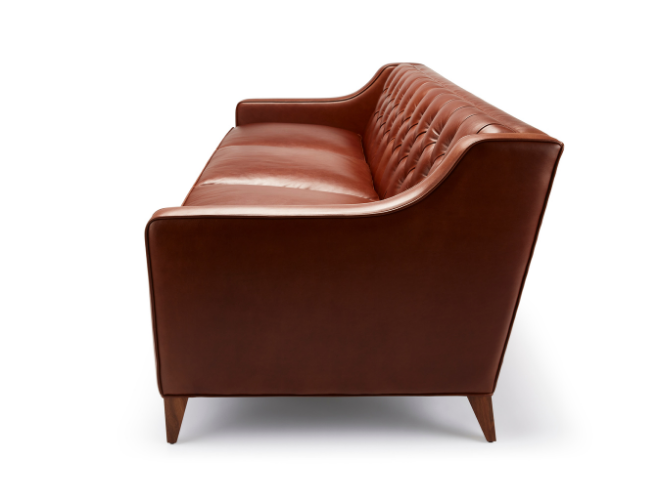 Brown leather sofa with button-tufted back and wooden legs, shown from the side against a white background.