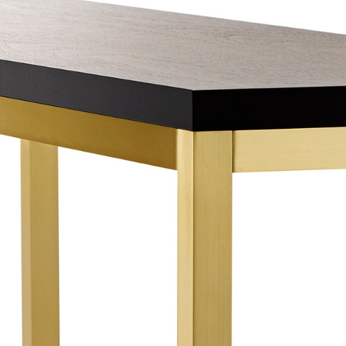Close-up of a modern table with a light-colored wooden tabletop, black accent trim, and gold-colored metal legs.