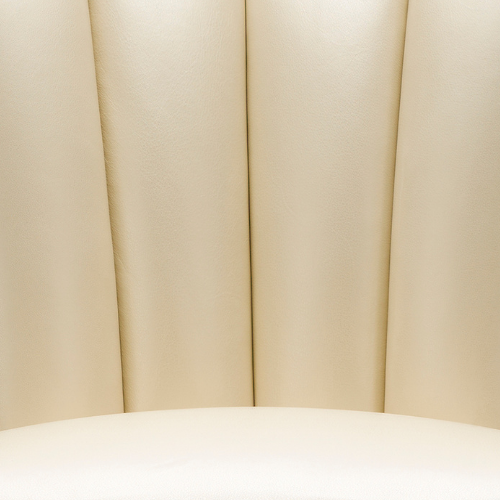 Close-up of cream-colored padded headboard with vertical seams.