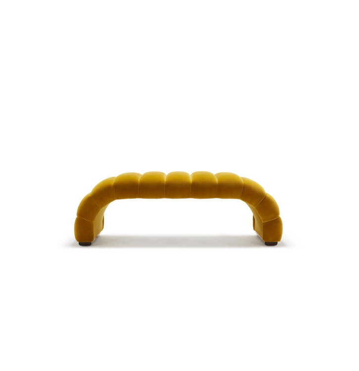 A modern, yellow, upholstered bench with a curved design, set against a plain white background.