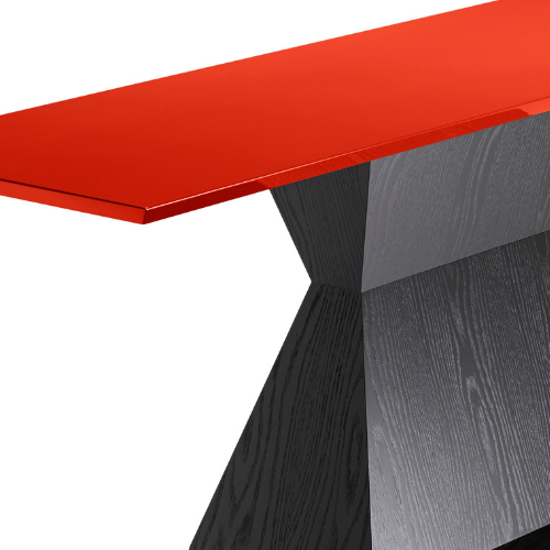 Close-up of a modern table with a red top and a black angled base.